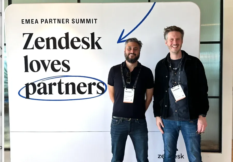 Tom Randle and Nick Smith standing in front of a “Zendesk loves partners” sign at Zendesk’s EMEA Partner Summit